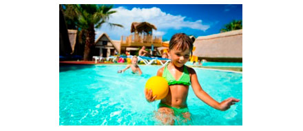 Flicka med en gul boll leker i en pool
