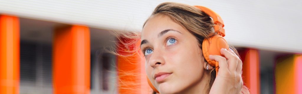 Ung kvinna med orange hörlurar tittar uppåt