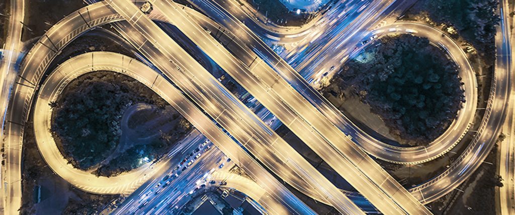 Flygbild av en upplyst motorvägskorsning i form av en åtta i skymningen